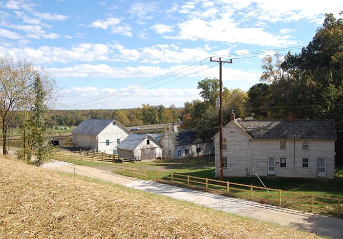 The Woodlawn barn complex in its current configuration. At right is the historic Otis Mason House, which the Federal Highway Administration moved from its nearby original site. At the far left is the historic “bank barn,” so named because of its location on the sloping bank of the hill. That allows simple access to both the upper and lower levels. The smaller structure in the middle is the corn crib, with the dairy between it and the house. The new Route 1 bypass is in the background.