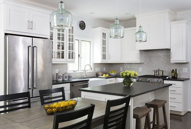 Black granite countertops and white cabinetry help modernize this Herndon kitchen by Winn Design + Build.
