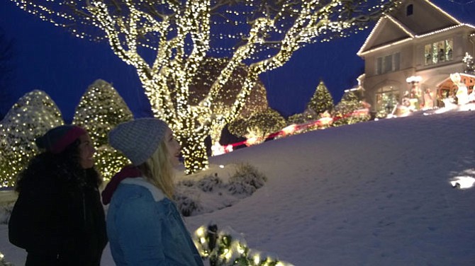 Maria Chavez, 29, of Arlington and Erin McGrath, 23, of Fairfax are enchanted Saturday by a brilliant Christmas light display as snow falls Dec. 9 in Reston at 11303 Stones Throw Drive. 