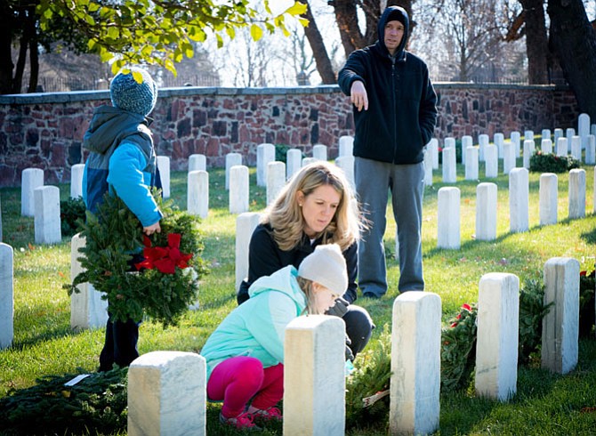 Volunteers place a wreath at a gravesite in Alexandria National Cemetery Dec. 16 as part of the nationwide Wreaths Across America event.