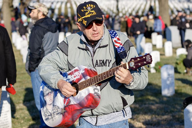 Craig Gross of Tarpon Springs, Fla., plays a song at his son’s gravesite during the Dec. 16 Wreaths Across America event at Arlington National Cemetery. CPL Frank R. Gross was killed by an IED while on patrol in Afghanistan on July 16, 2011.
