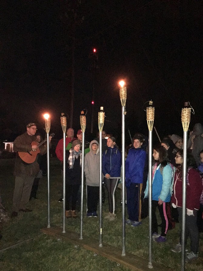 Cantor Henrique Ozur Bass leads students in song Tuesday at the first night lighting of the Menorah at Congregation Har Shalom on Falls Road.