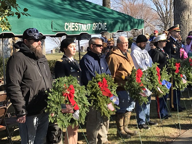 Standing in front of the Remembrance Wreaths during the National Wreaths Across America Day ceremony at Chestnut Grove Cemetery are (from left) Sgt. First Class Josh Smith, United States Army, Retired, representing POW/MIA with Shelby, service dog, Major Maria Bingham, United States Army, representing United States Merchant Marines, Lt. Alexander Austin, United States Coast Guard, Spec 4 Edward Greer, United States Army, representing United States Air Force, Chief Petty Officer; United States Navy, Retired, Christian Myers; Capt. Mia Hencinski, United States Marine Corps; and Major Thomas Lane, United States Army.
