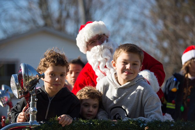 Santa, Elliot Zaret of Great Falls, pictured with Vienna neighborhood residents, (from left) Jacob Lucca, 7, Thomas Lucca, 5, and Logan Lucca, 9, on the classic fire truck for a Santa run Saturday, Dec. 16 in Vienna.