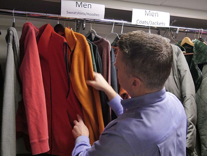 Scott Miller, senior development director for A-SPAN, sorts through the racks of sweatshirts and jackets in the clothing room at the center. He says Arlington Realtors Care (ARC) recently donated a lot of heavy jackets to the center. 