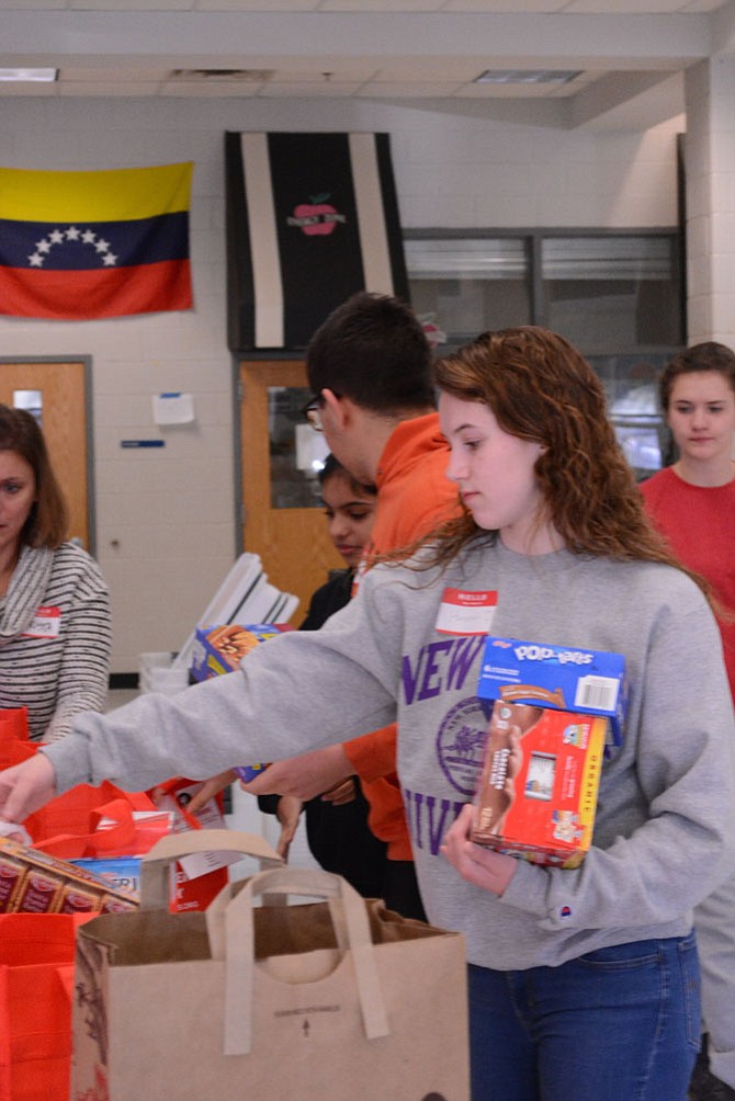 Herndon High senior Hannah Overton sorts food for delivery to area schools. Hannah is one of the many, reliable teen volunteers who have helped to make Food For Neighbors a success.