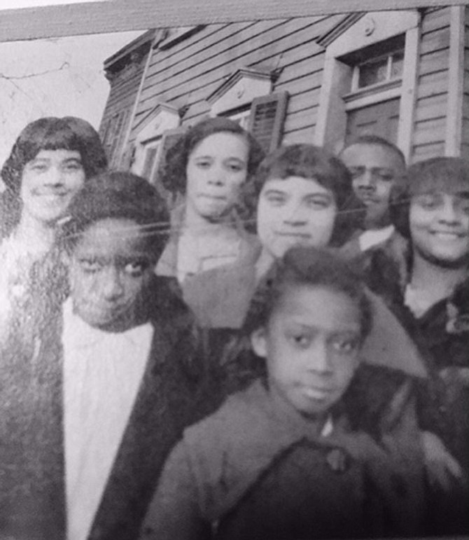 Estelle Lane with her family and friends outside of her house at 417 North Henry St. Estelle Lane is in the center of the picture with bangs (she is directly behind the little girl in the center on the front row) taken around 1930.