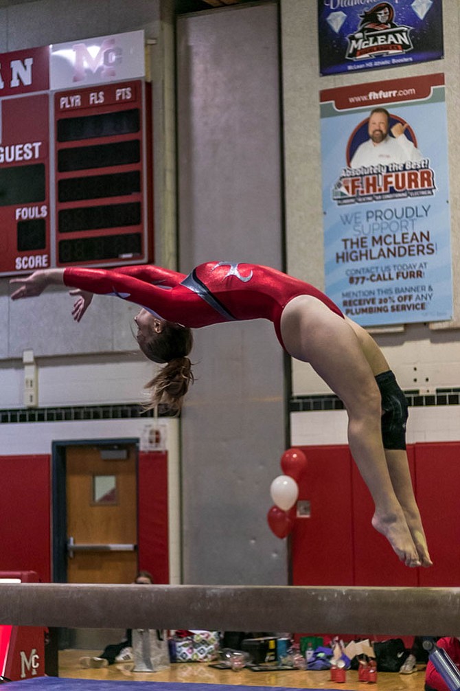 Tara Stewart jumping backwards during her first place performance on the balance beam, scoring a 9.55.