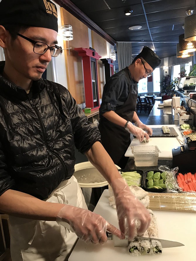 At the Grand Opening of Red Kimono Japanese & Korean Cuisines held Friday, Jan. 26, 2018, Sushi Chef, Zhen Chen of Vienna (front) slices rows of sushi while Head Sushi Chef, Dongsoo Kim of Centreville begins to prepare another set.