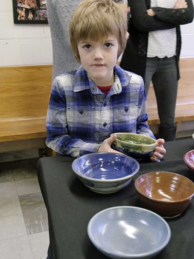 Colin Smith walks around the table studying each bowl and finally chooses a green one. 