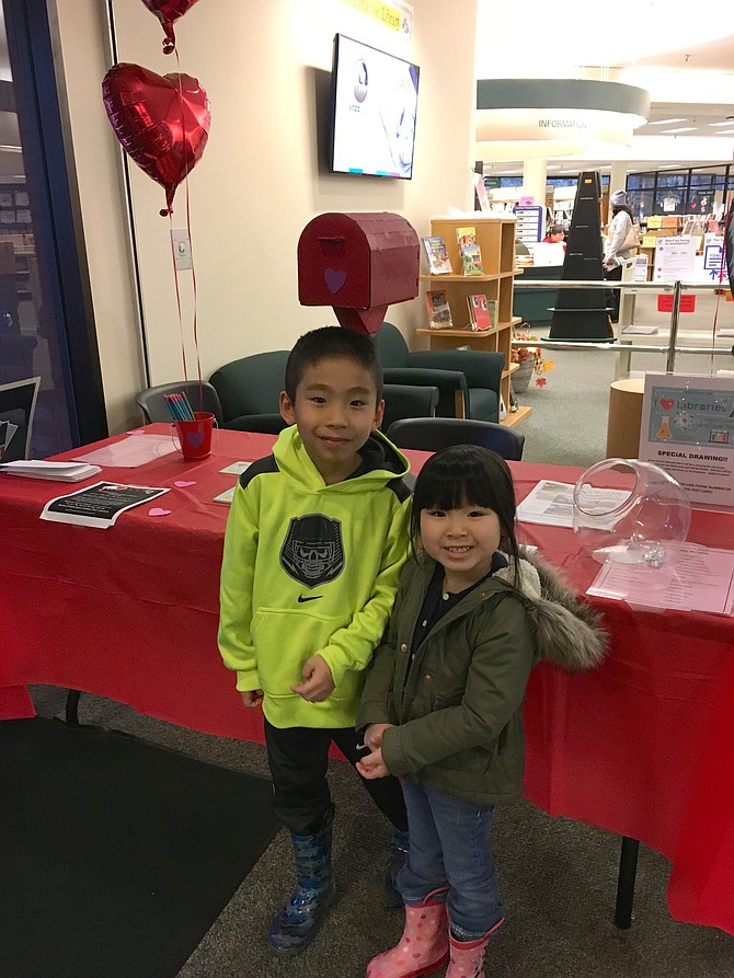 Lucas Nguyen, 7, and his sister Lilymay, 4, pose by the Library Lovers Month display table at the Library Potomac on Saturday.