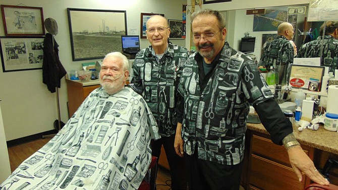 Customer Neal Nelson gets his haircut by owner Bob Stockton, with Leo Dodson (right).