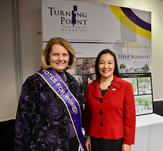From left: Patricia Depew Wirth, executive director of the Turning Point Suffragist Memorial organization, and Herndon Town Council member and Commission for Women 2018 honoree Grace Cunningham in front of the display highlighting the designs for the national memorial planned for suffragists, to be built in the Occoquan Regional Park in Lorton.