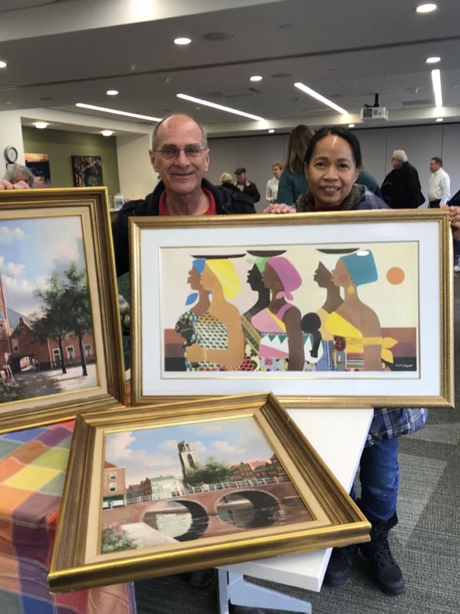 Ed and Gina Bolston, of Reston, former Herndon residents, show off the art treasures they found leaning against someone's trash can in Herndon. The works of art were identified at the Appraisal Roadshow in Reston as two original oil paintings by George Jan Dispo, a German artist and a  signed lithograph by nationally recognized American artist Varnette Honeywood (1950-2010).