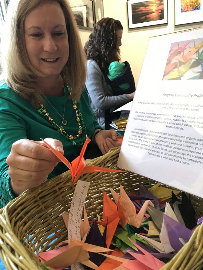 Elizabeth Vosseller drops one of her origami cranes into a box. Vosseller and her clients at Growing Kids Therapy Center in Herndon need 1,000 cranes to create a work of art in support of autism acceptance and awareness.