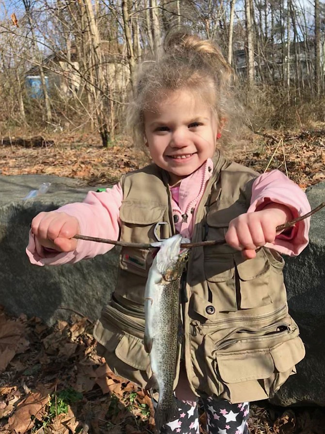 Olivia Gallihugh, 4, of Manassas, holds up one of three trout she caught in Snakeden Branch Stream during Reston Association  Annual Kids’ Trout Fishing Day held Saturday, March 24, 2018.