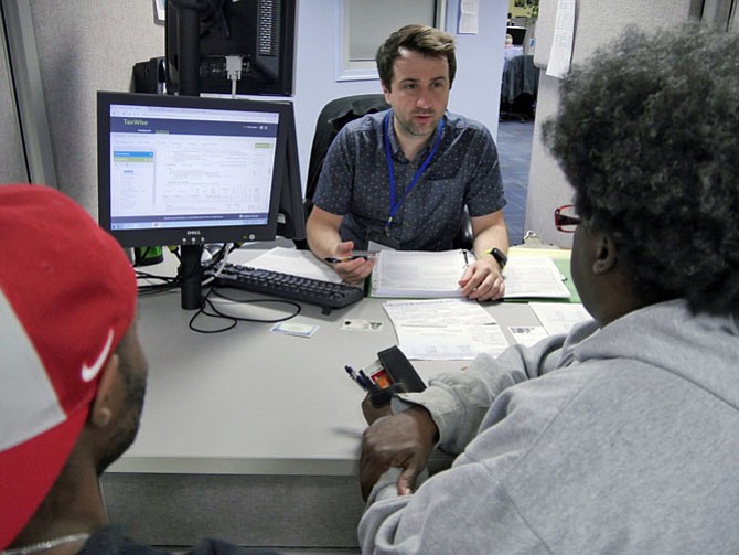 Chris Sharp, a first-year volunteer with the Virginia Income Tax Assistance program, is assisting a family with a standard 1040 form. 