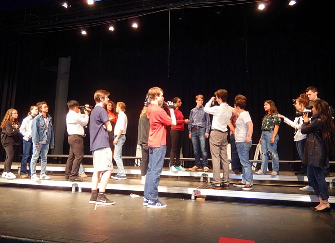 Cast members portray TV news crews interviewing the townspeople of Laramie.