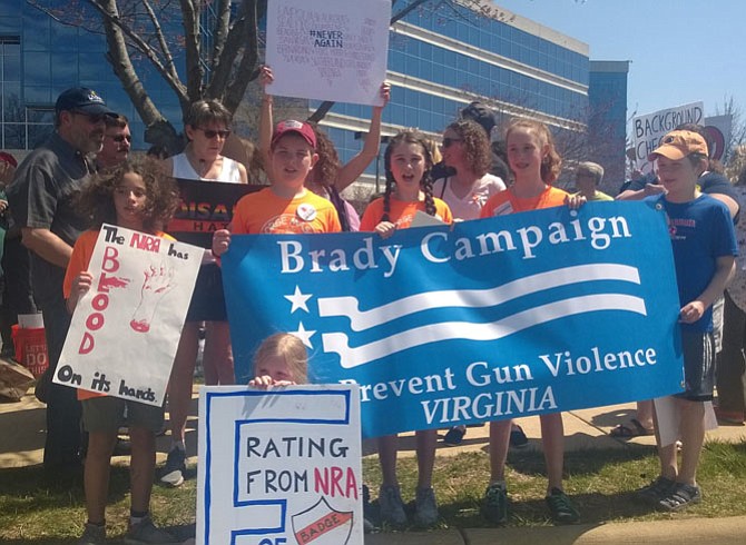 Fifth graders from George Mason Elementary School in the City of Alexandria say “We want change” to lawmakers Saturday afternoon as they stand up to the nation’s largest gun lobby at a protest April 14 in Fairfax at the National Rifle Association headquarters on Waples Mill Road.  Four students took turns speaking to concerned citizens, who have decried gun violence each month since the Dec. 14, 2012 mass shooting that killed 20 children and six adults at the Sandy Hook Elementary School in Newtown, Conn.  Budding orators in safety orange T-shirts — the protective color universally recognized by hunters — are, from left:  Elisabeth Peyton, 11, Matthew Heckel, 10, Casey Donahue, 11 and Lily O’Neil, 11. At the end of their talk, the four stood together with their arms interlocked:  “We are strong but we are stronger together,” they told listeners.