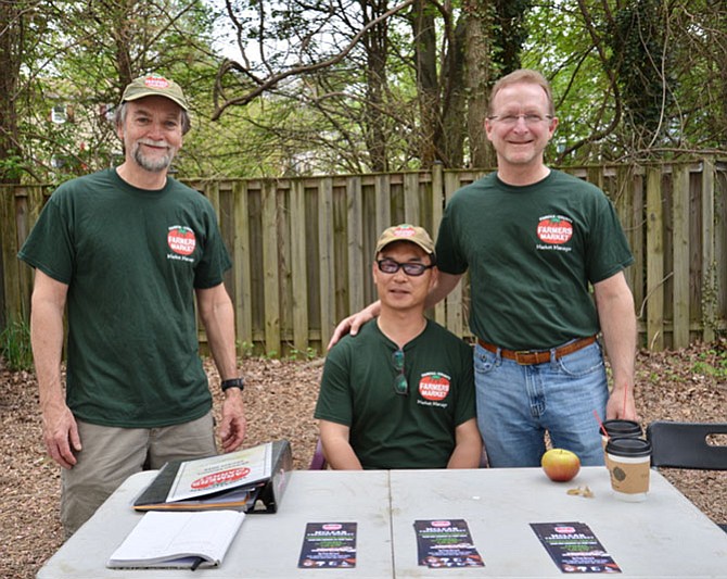 Your McLean Farmers Market welcoming committee. Standing, from left: market manager, Bob Baldwin and assistant manager Bill Smith; seated, Yong Gong, a recent, temporary transplant from South Korea, and self-described “assistant to the assistant.” Together they run the show, helping vendors and visitors alike.