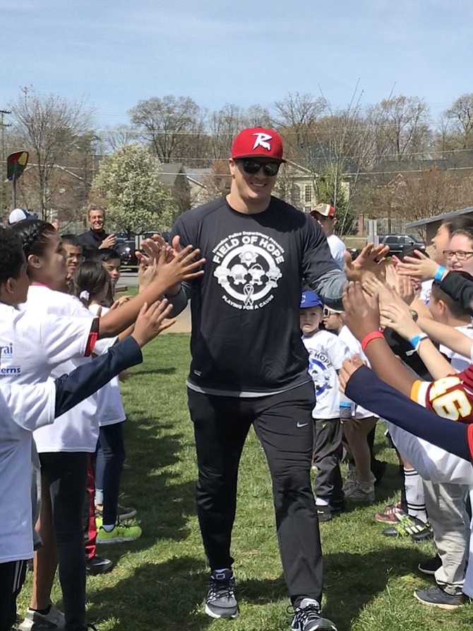 Ryan Kerrigan, #91 Linebacker of the Washington Redskins, high-fives youth at Herndon Police Department Field of Hope, Playing for a Cause, a fundraiser for SafeSpot Children's Advocacy Center of Fairfax.