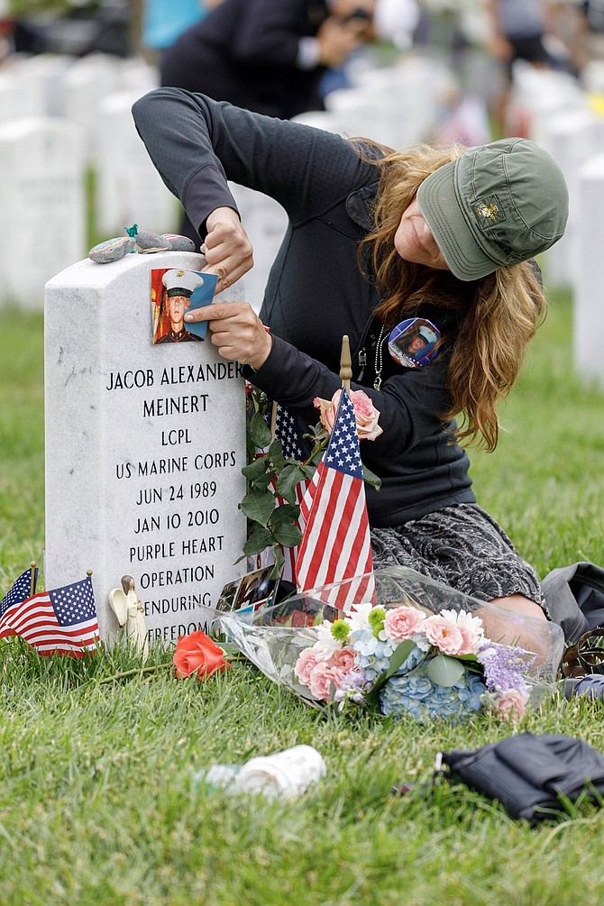 Randi Meinert of Racine, Wisc., places a photo of her brother Jacob on his headstone in Section 60 of Arlington National Cemetery following the Memorial Day ceremonies May 28. Lance Corporal Jacob Meinert was killed Jan. 10, 2010, when he stepped on a land mine while serving with the U.S. Marines in Afghanistan.