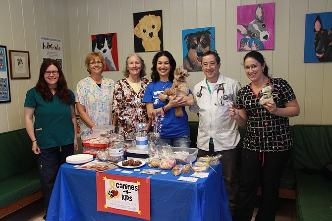 Kendra Gehringer, Christine Randall, Donna Koch, Candice Bhatia and her dog Buttercup, Eric Newhart and Sheri Virgulak as they stand behind the bake sale table at the VCA Animal Hospital.