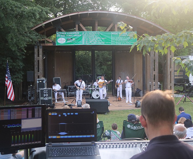 Music technician works the soundboard as Navy band plays in the background.