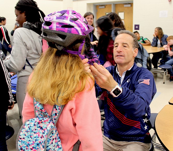 Abrams Landau, Ltd. attorney Doug Landau fits a brand new bike helmet on a student for his Lids on Kids program.