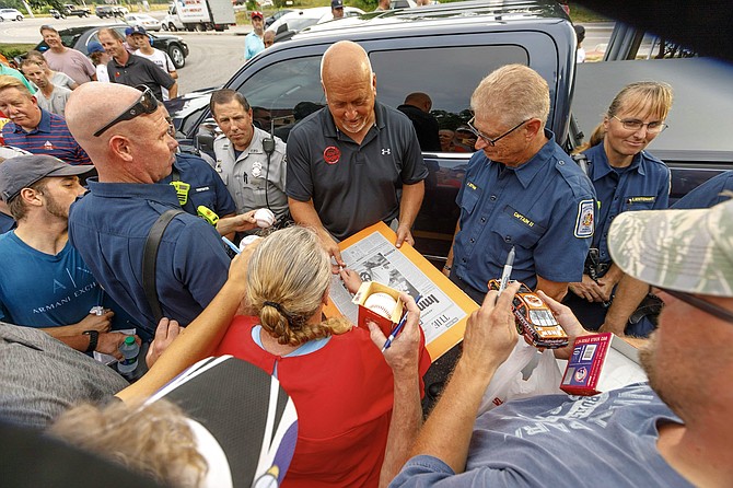 Cal Ripken Jr., center, signs a piece of memorabilia for retired Fairfax County firefighter Karrie Boswell as other police and fire personnel look on during a July 16 appearance by the baseball legend at Roy Rogers Restaurant in Alexandria celebrating the franchise’s 50th anniversary.