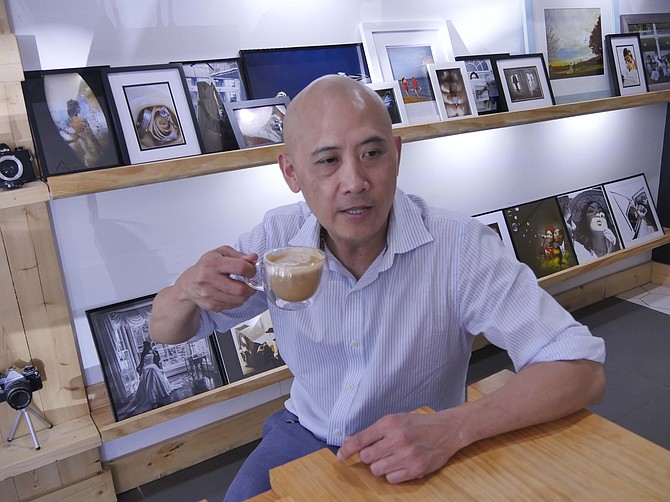 Daniel Bui, owner of Chill Zone, sits in front of the wedding pictures he has taken in his photography business.