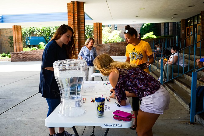 Students gather around the tables to sign the banners for the students to provide thoughts and recognition. 