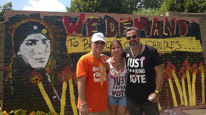 From left:  South Florida residents Fred Guttenberg, and Patricia and Manuel Oliver support each other Saturday afternoon at the March on NRA protest in Fairfax. Guttenberg lost his 14-year-old daughter Jaime Guttenberg, to a mass shooter Valentine’s Day at the Marjory Stoneman Douglas High School in Parkland, Fla. — where the Oliver’s son, Joachim Oliver, also was killed. Aug. 4 would have been Joachim’s 18th birthday and his life was celebrated with song, cake and a graffiti wall spray painted during the rally with his image and the message: “We demand to blow out our candles.”