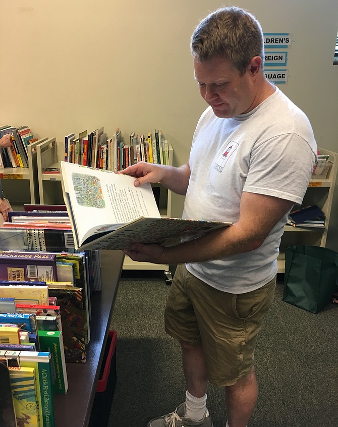 Cameron Rittenhouse-Smith browses the children’s book section at the Potomac Library Book Sale on Saturday, Aug. 11. He said he started a program to give books to children in foster care in Washington County, Md.