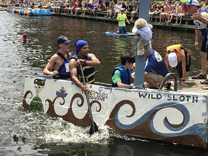 A wake of waves crashes as “River Sea Chocolates Wild Sloth” docks at the pier at the 2nd Annual Lake Anne Cardboard Boat Regatta held Saturday, Aug. 11. Later during the awards ceremony, the team accepted the Skipper First Place Award, finishing with an astounding time of 2:05.