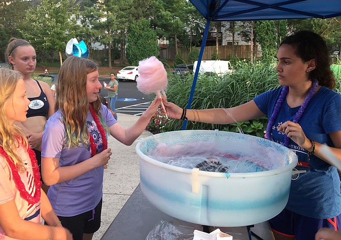 Westfield High sophomore Grace Marvin (far right) hands cotton candy to a customer at Sully Station II.