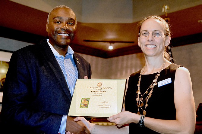 E. Sean Lanier, President of the Rotary Club of Springfield, presents a certificate which denotes a book given to the Library at Garfield Elementary School, to Jennifer Jacobs, Co-Founder & CEO of Connect Our Kids, located in Falls Church.