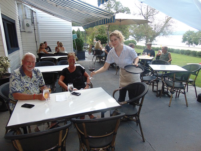 Caroline Anderson serves wine to Cliff and Debbie Conway on the terrace of Cedar Knoll Inn at 9030 Lucia Lane.