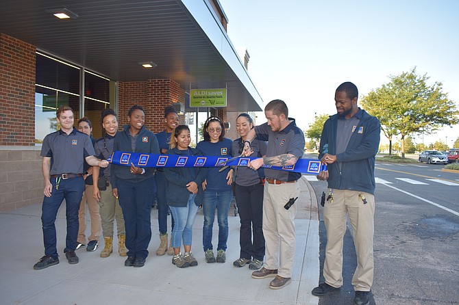 Store Manager Logan White cuts the ribbon to celebrate the grand opening of ALDI in the Fair Lakes Shopping Center.