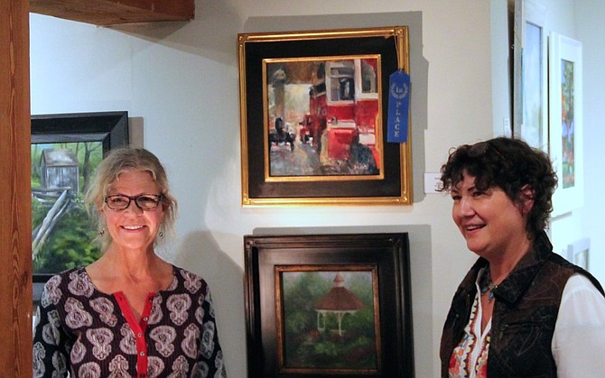 Jill Banks stands next to her winning painting “Station 12” with competition judge Lynn Mehta.