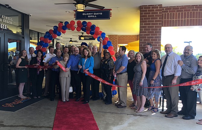 Mayor Allison Silberberg, center with scissors, leads a crowd of dignitaries and supporters in cutting the ribbon to officially open Glory Days Grill Sept. 6 in the Alexandria Commons Shopping Center on Duke Street. The location is the company’s 33rd and 15th in Virginia.
