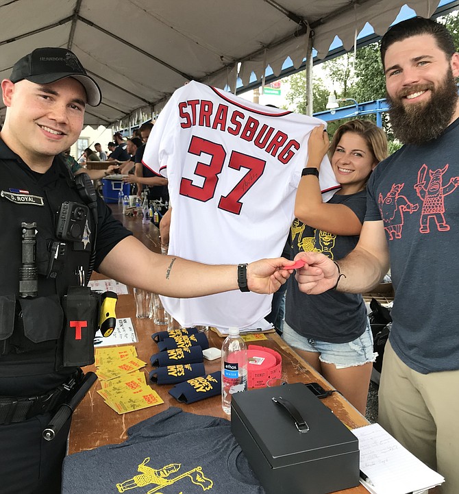 Town of Herndon officer PFC D. Royal is handed a raffle ticket, one he hopes will win the signed Strasburg jersey donated by Aslin for their 3rd Anniversary celebration and to support Wade's Army. Wade's Army was founded to champion the life of Wade DeBruin (2009-2011) and honors his battle against neuroblastoma and fights pediatric cancer.