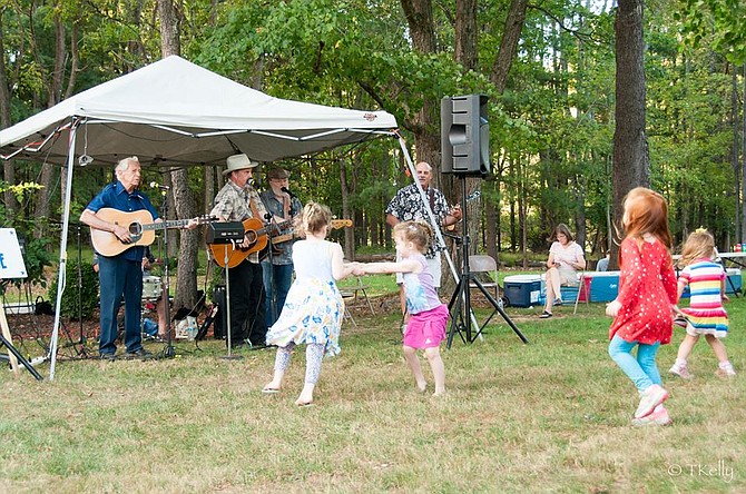 Children take a break from pumpkin painting to dance with the bluegrass music of the Andrew Acosta Band.