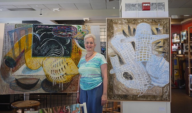 Sue Grace stands in front of two of her paintings hanging at the pop up art gallery in the 2800 block of Clarendon Boulevard, across from Orvis. Studio space is hard to come by in Arlington, and these artists are grateful for the time they will have in this space. Grace likes the diffuse light in the studio. For more information see www.suegrace.com