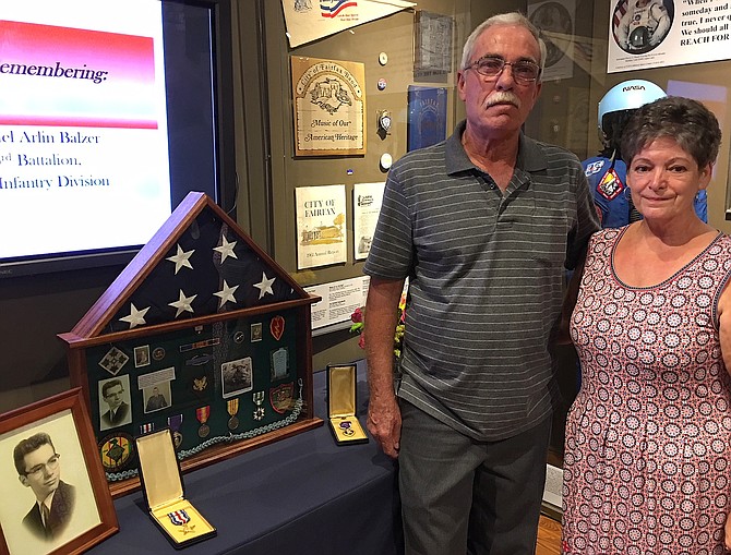 Kim and Debbie Balzer stand beside the display honoring Kim’s brother Michael, including his photo, shadowbox of medals, Silver Star and Purple Heart.