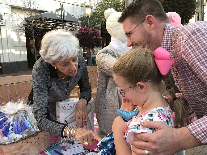 Reagan Crozby, 7, bids on a raffle item hoping to win it as a gift for her mother, Stephanie Stephens Crozby. With Reagan is her dad, Brian Crozby. "My wife is a cancer survivor, and she is in the show," he said.
