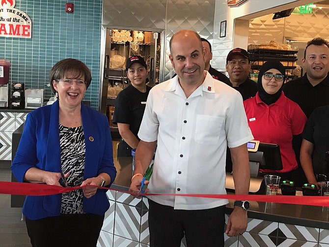 Supervisor Kathy Smith (D-Sully) and District Manager Frank Costello cut the ribbon on the new Habit Burger, while female employees (from left) Jenne Mendez and Alicia Lizama look on.