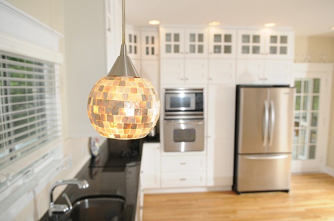 In a coastal home, interior designer Anne Walker chose Capiz shell chandeliers over the dining table and Capiz shell pendants over the kitchen counters. “The result was beautiful and the cost was effective,” she said.