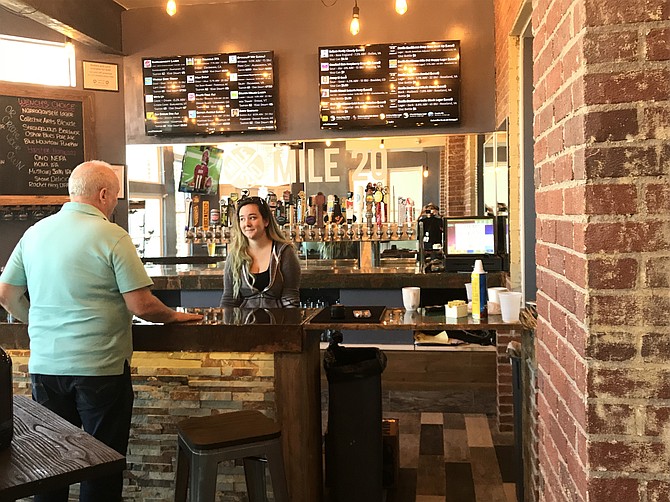 A future patron of Mile 20 stops in before the official opening to chat with the bartender, Kati Simpson, and preview the inaugural tap list.
