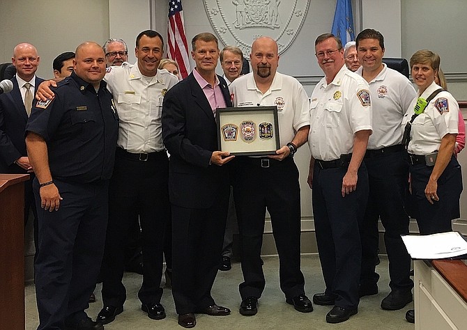 City Fire Department personnel present Jeff Greenfield with framed fire and police patches.